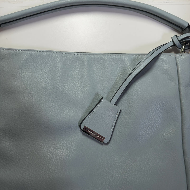 Tag view of sage green David Jones Paris crossbody bag worn on shoulder, showing structured silhouette and strap adjustment