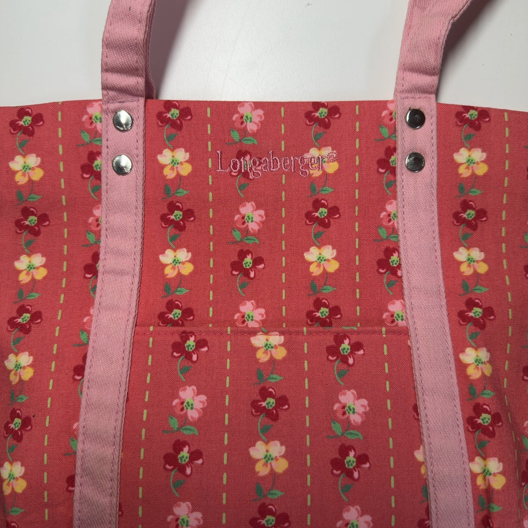 Red floral canvas Longaberger shoulder tote bag worn on shoulder, back view displaying full floral design and pink canvas handles