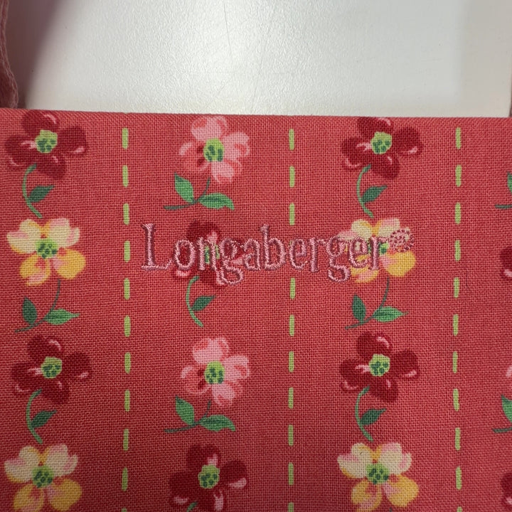 Red floral canvas Longaberger shoulder tote bag worn on shoulder, back view displaying full floral design and pink canvas handles