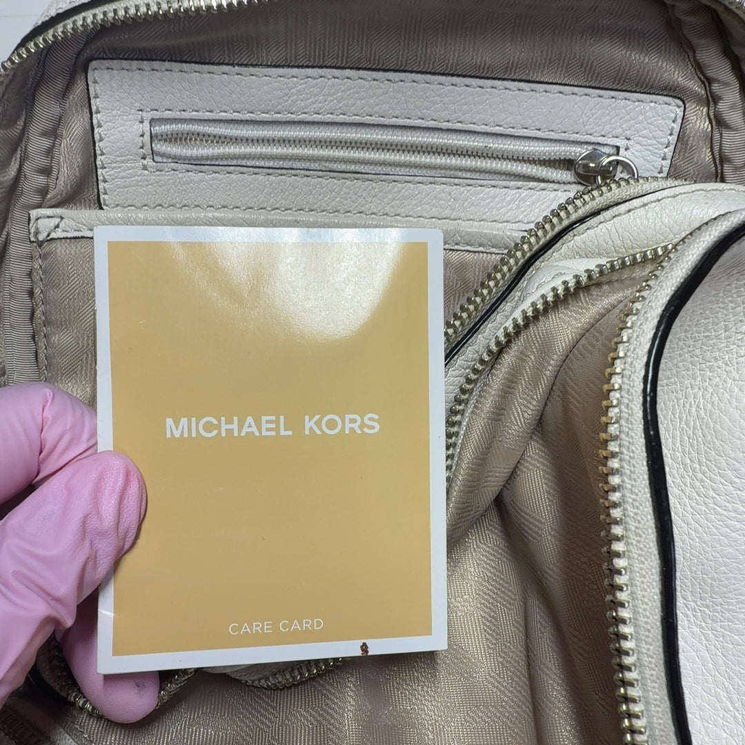 Cream and black Michael Kors leather backpack worn on back with padded shoulder straps, rear view