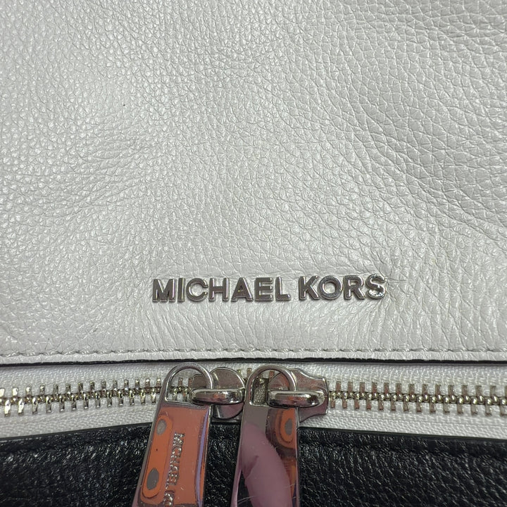 Cream and black Michael Kors leather backpack worn on back with padded shoulder straps, rear view