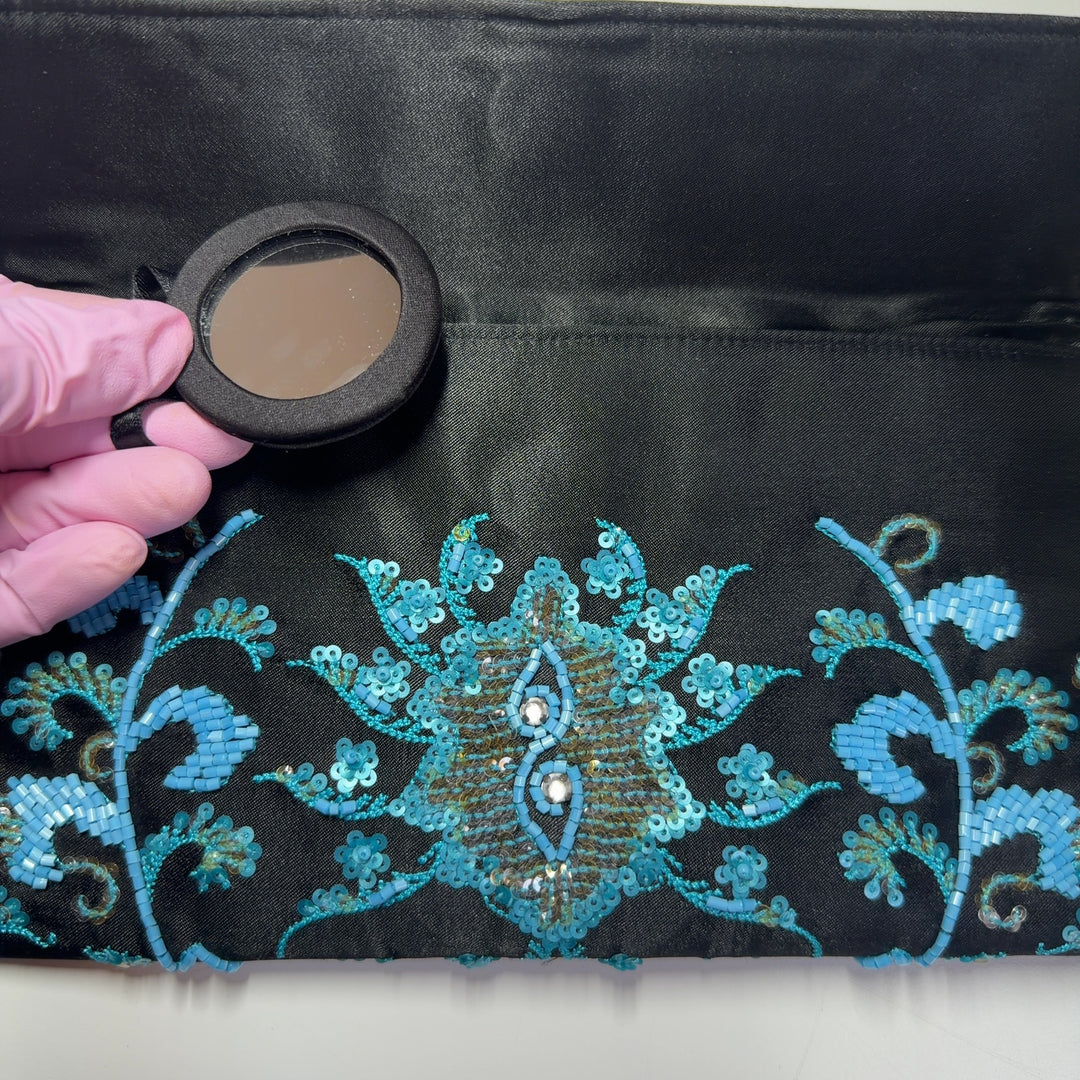 Tag view of black turquoise embroidered crossbody wallet worn as a crossbody bag