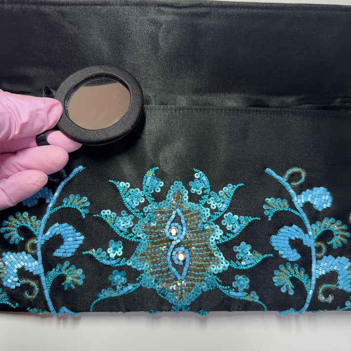 Tag view of black turquoise embroidered crossbody wallet worn as a crossbody bag