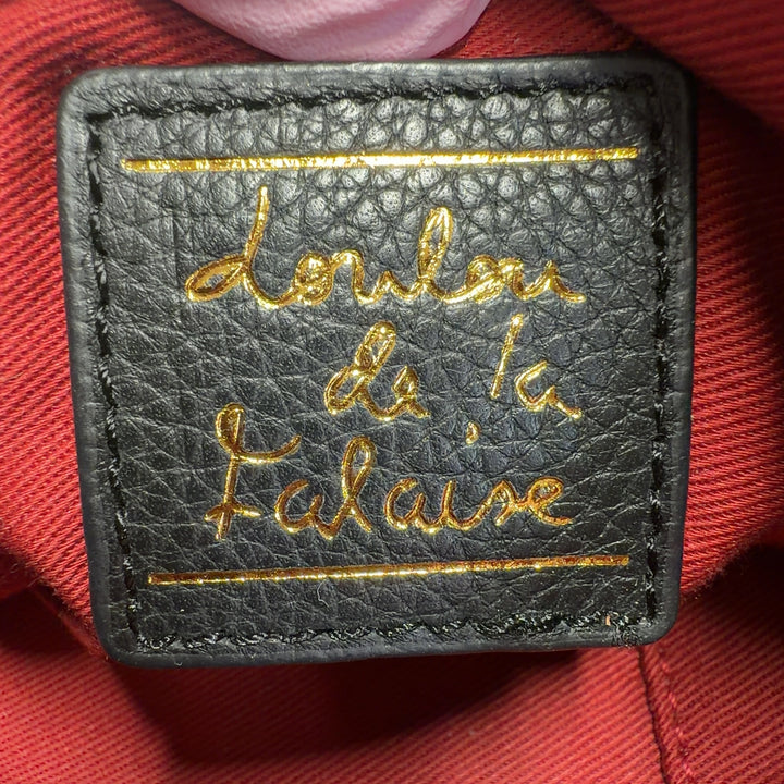 Tag view of black studded leather crossbody bag worn on shoulder showing studded strap detail