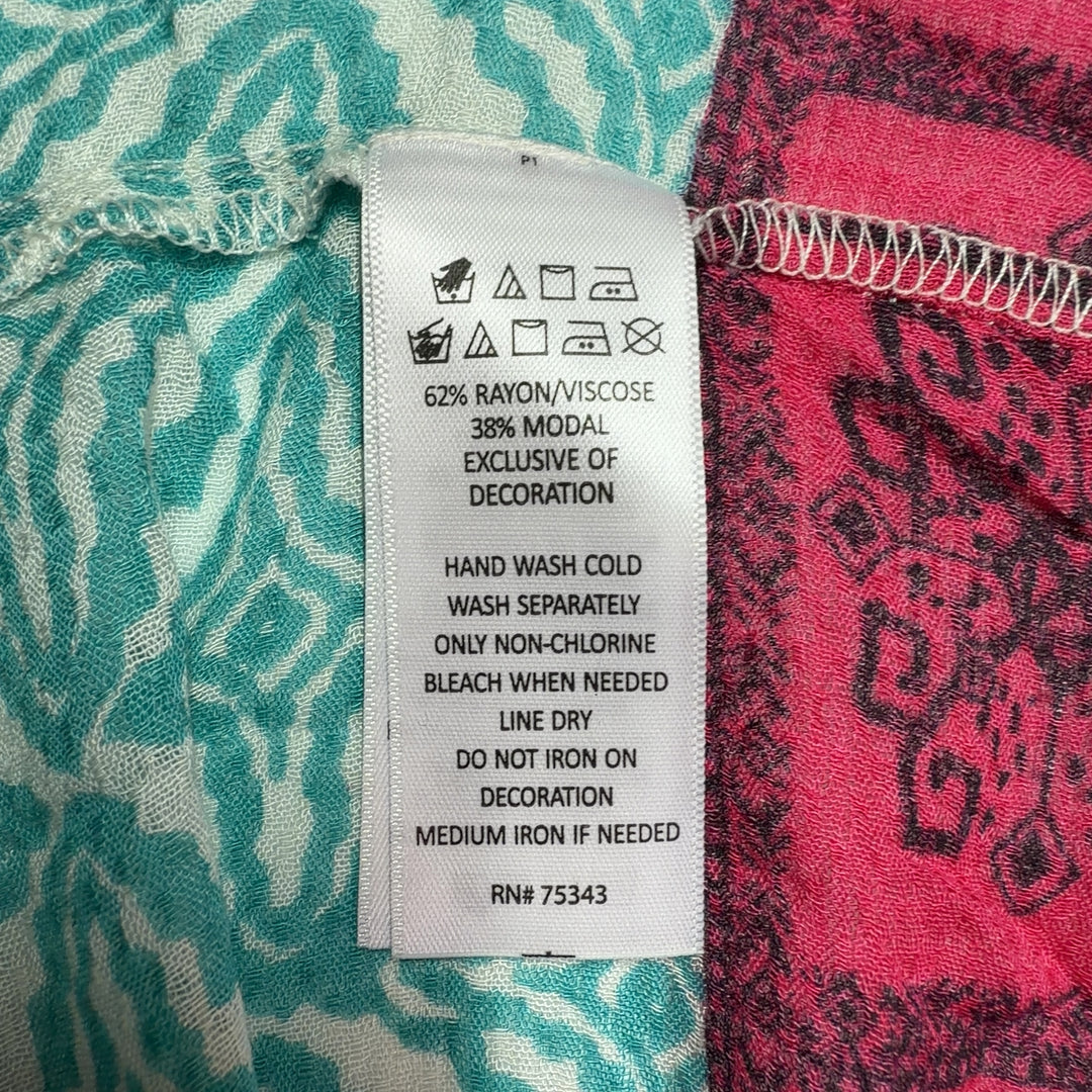 Tag view of turquoise floral tunic top showing relaxed fit and pink patterned border hem detail