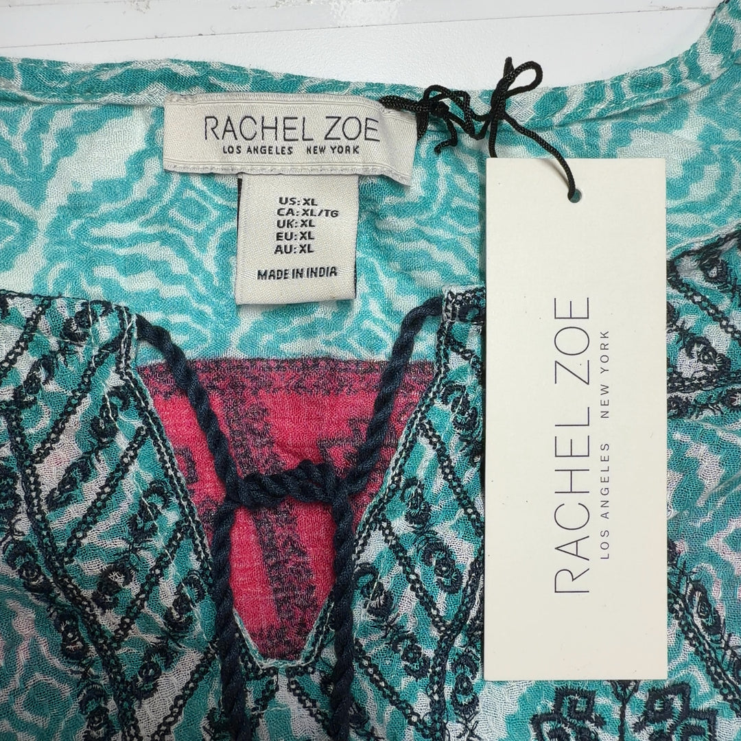 Tag view of turquoise floral tunic top showing relaxed fit and pink patterned border hem detail