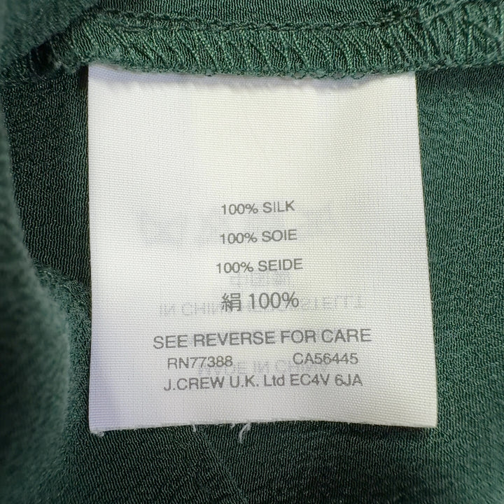 Tag view of green silk ruffle sleeve blouse showing layered sleeve detail and relaxed silhouette