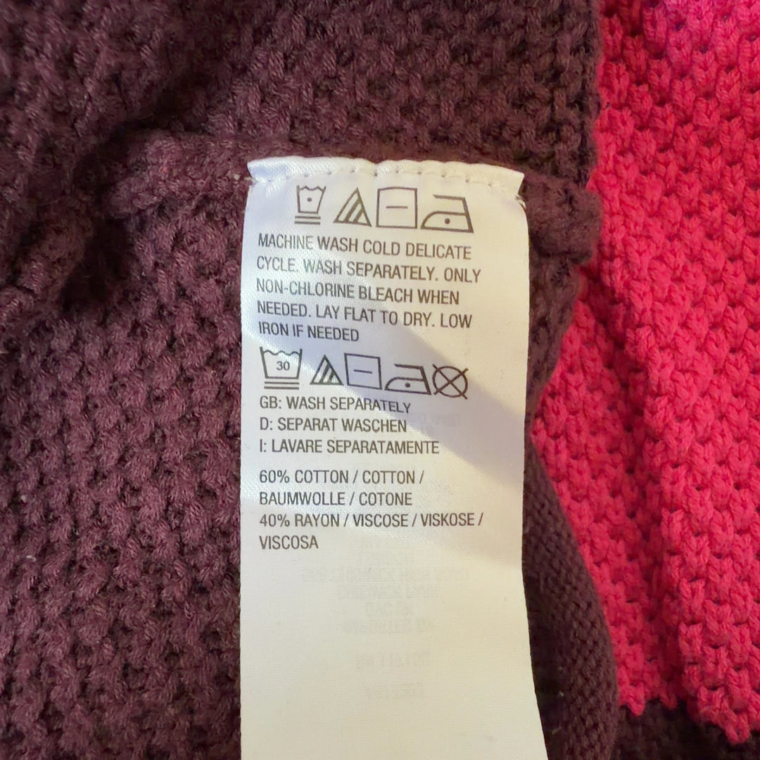 Tag view of orange colorblock knit pullover sweater showing horizontal stripe design and relaxed fit