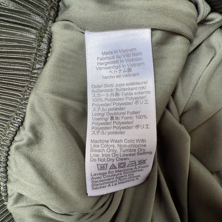 Tag view of green pleated midi skirt showing the elegant drape and length of the pleated design