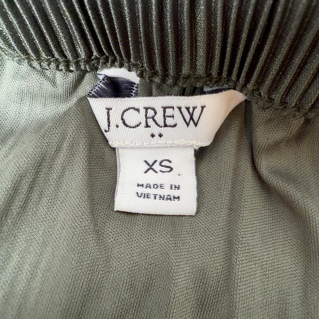 Tag view of green pleated midi skirt showing the elegant drape and length of the pleated design