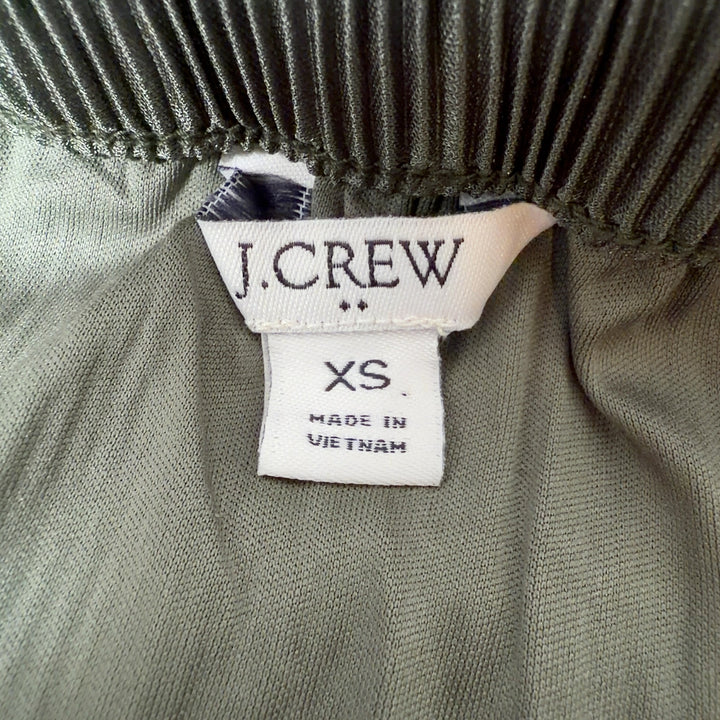 Tag view of green pleated midi skirt showing the elegant drape and length of the pleated design