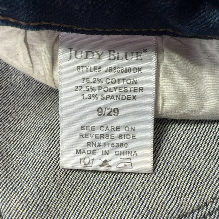 Tag view of blue distressed denim jeans showing classic five-pocket design and knee rip details