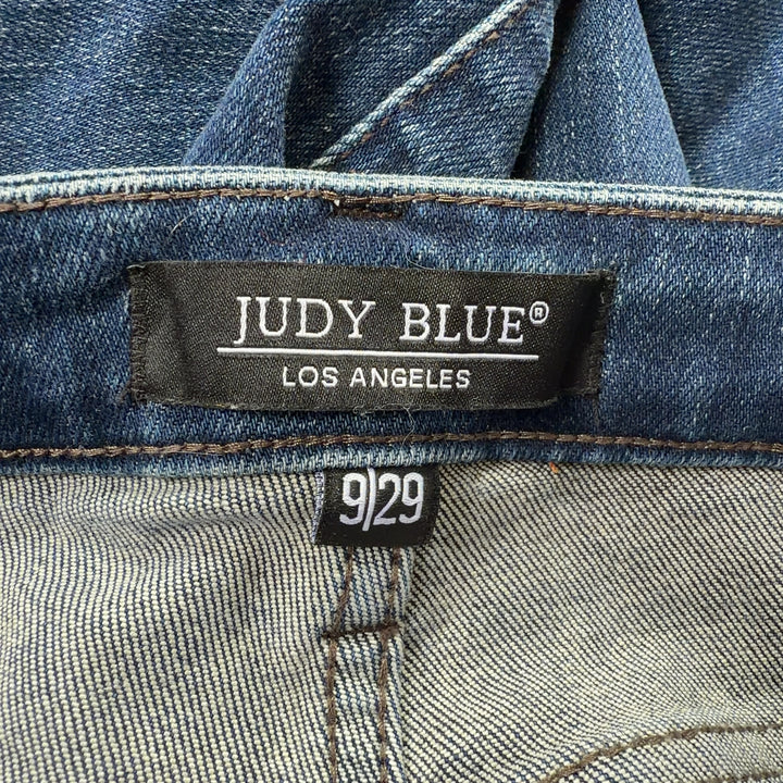 Tag view of blue distressed denim jeans showing classic five-pocket design and knee rip details