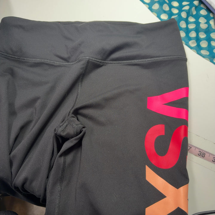 Black activewear leggings with vibrant neon colorblock design, back view showing full stripe pattern