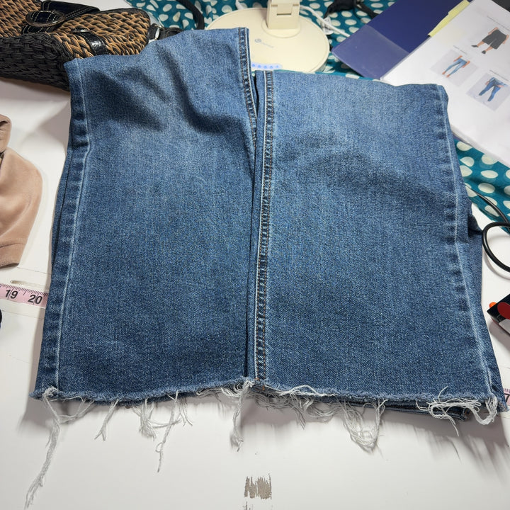 Tag view of blue denim cropped jeans showing straight-leg silhouette and distressed ankle hem