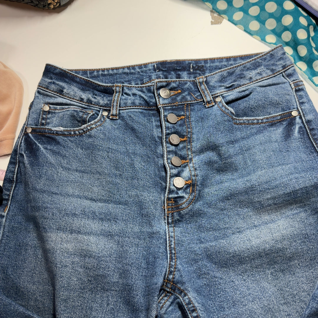 Tag view of blue denim cropped jeans showing straight-leg silhouette and distressed ankle hem