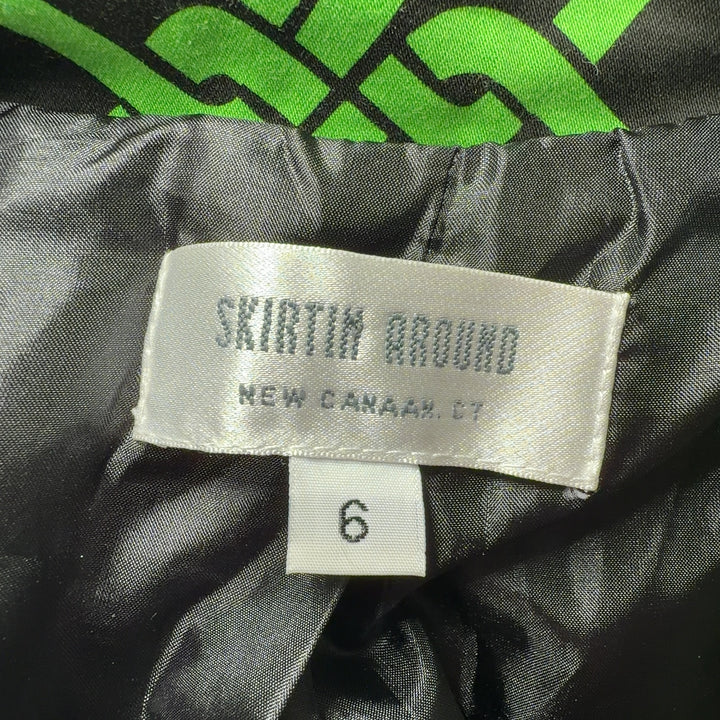Tag view of green geometric patterned jacket by Skirtin Around showing the full length and drape of the tailored design