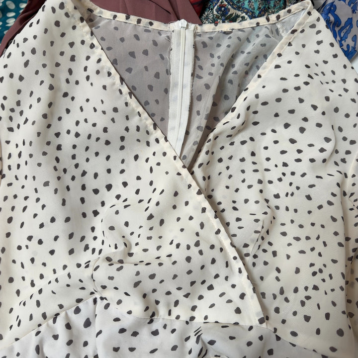 Tag view of cream polka dot wrap romper showing wrap design and ruffle hem detail