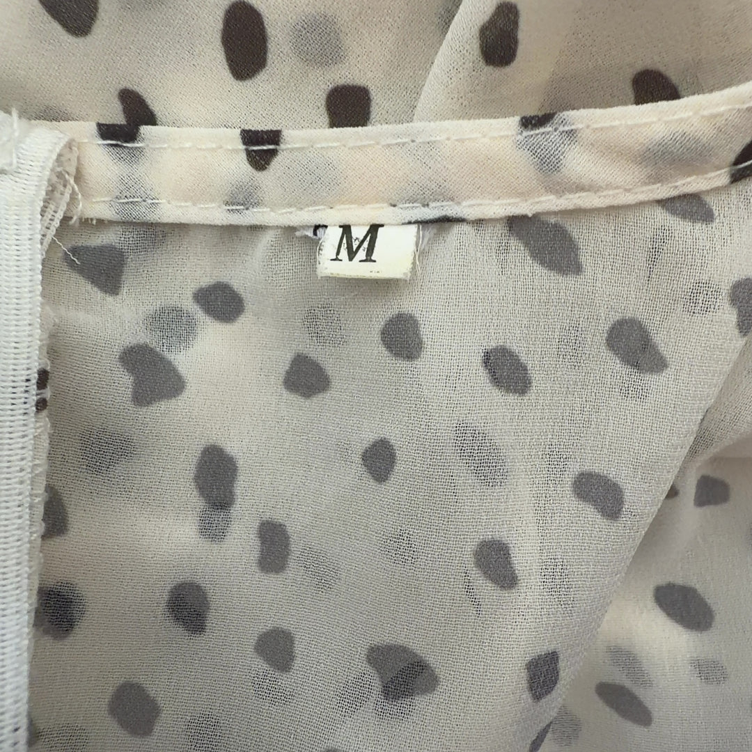Tag view of cream polka dot wrap romper showing wrap design and ruffle hem detail