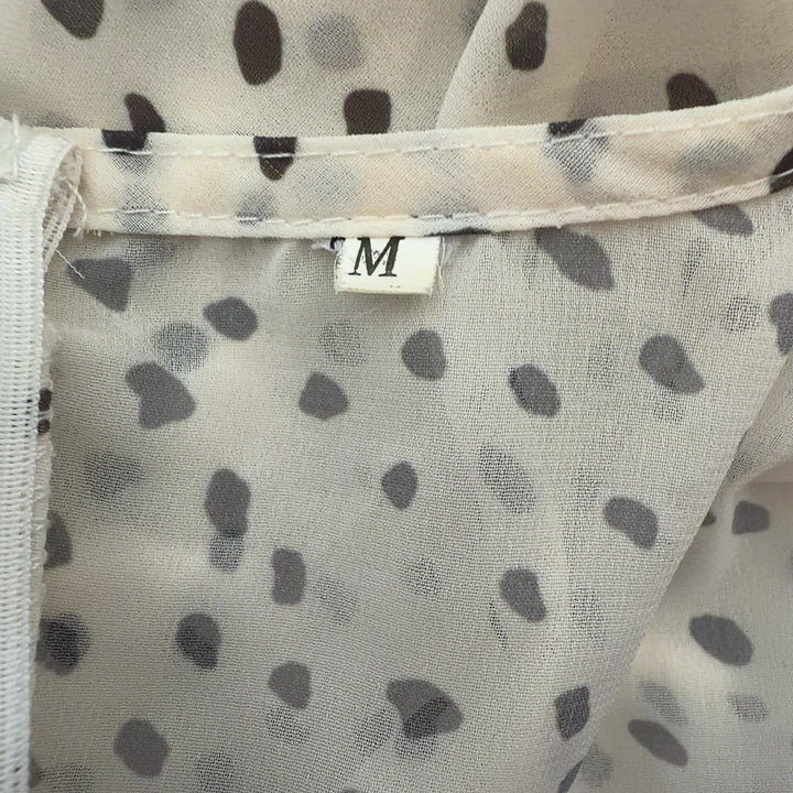 Tag view of cream polka dot wrap romper showing wrap design and ruffle hem detail