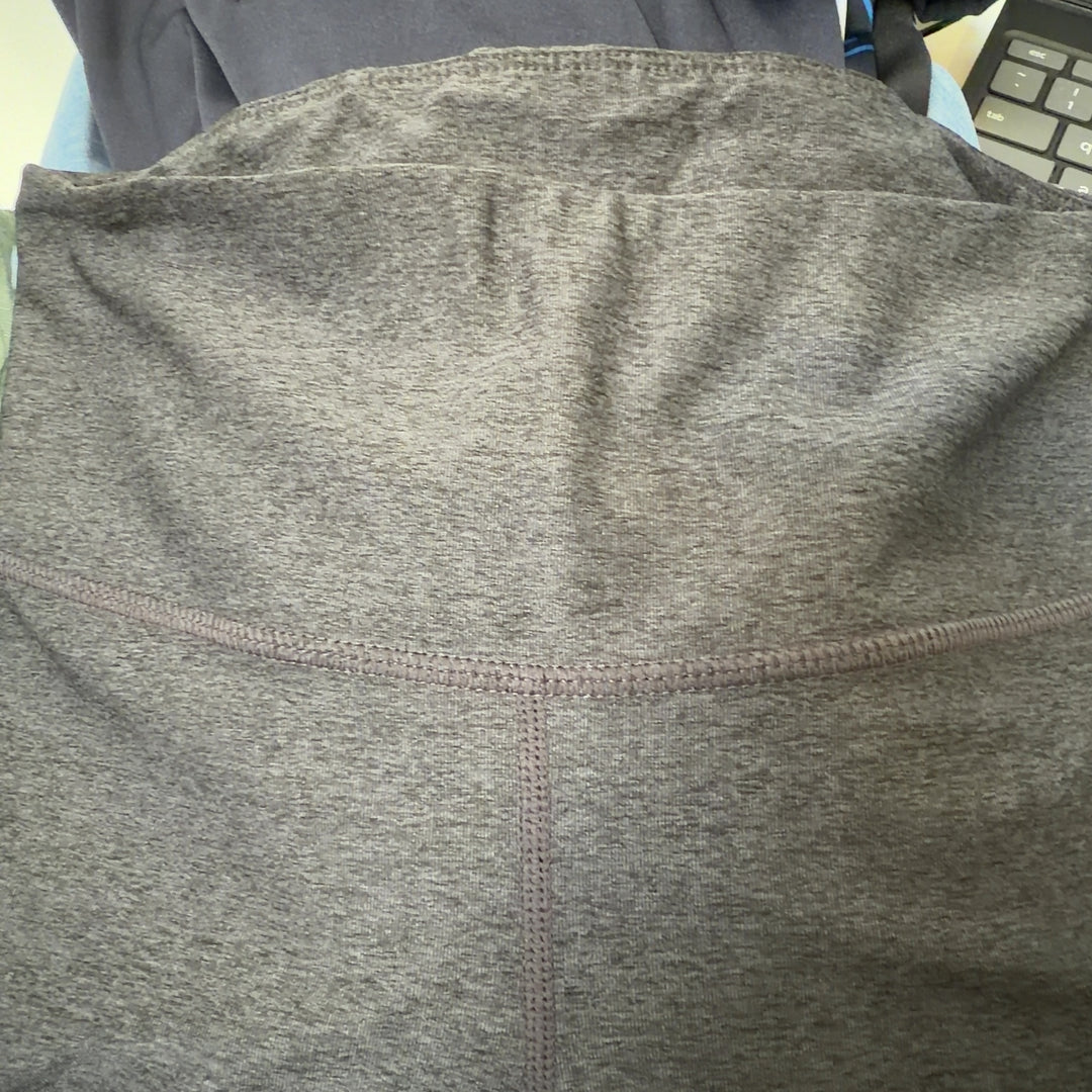 Tag view of charcoal capri leggings showing mesh panel details on calves
