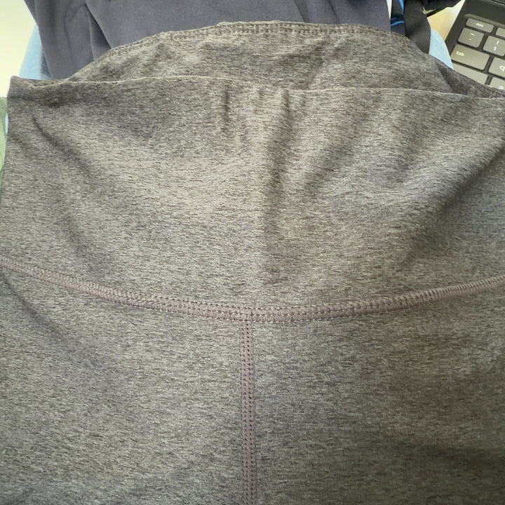 Tag view of charcoal capri leggings showing mesh panel details on calves