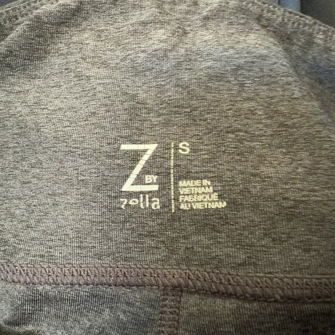 Tag view of charcoal capri leggings showing mesh panel details on calves