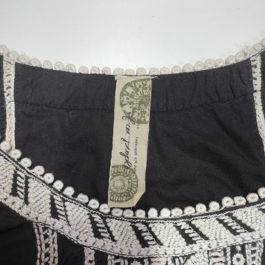 Black cotton Free People dress with white embroidered back neckline and cream trim hem, back view