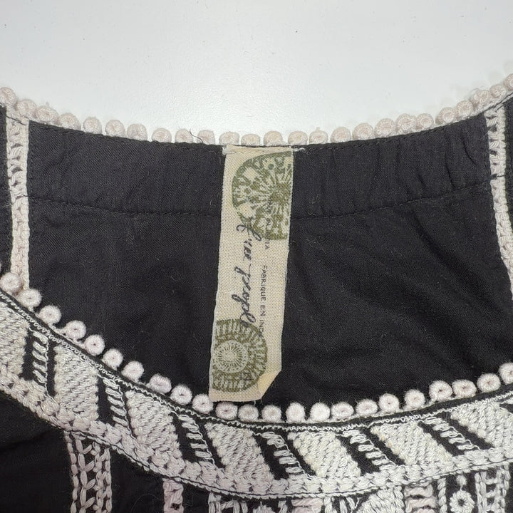 Black cotton Free People dress with white embroidered back neckline and cream trim hem, back view
