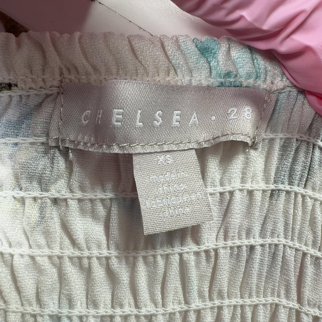 Tag view of cream floral off-shoulder dress showing gathered neckline and knee-length hemline with decorative trim