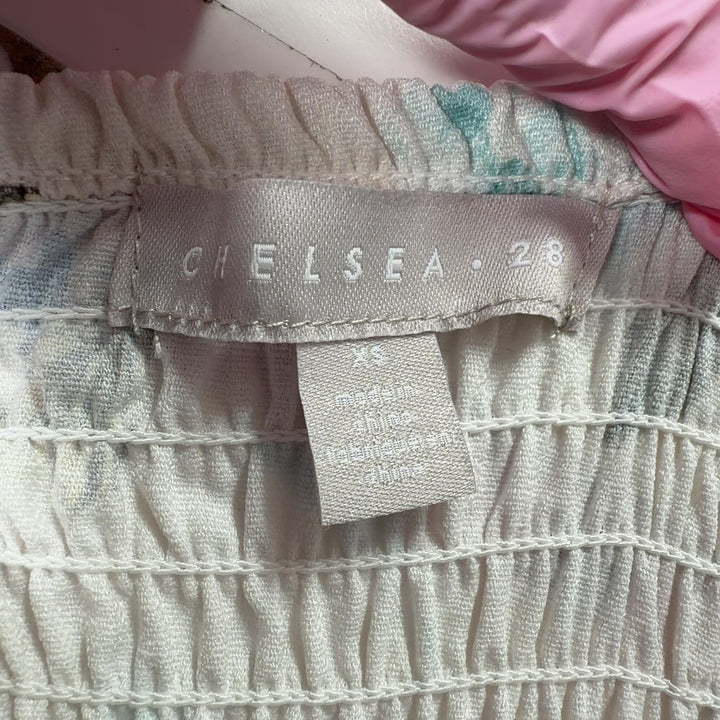 Tag view of cream floral off-shoulder dress showing gathered neckline and knee-length hemline with decorative trim