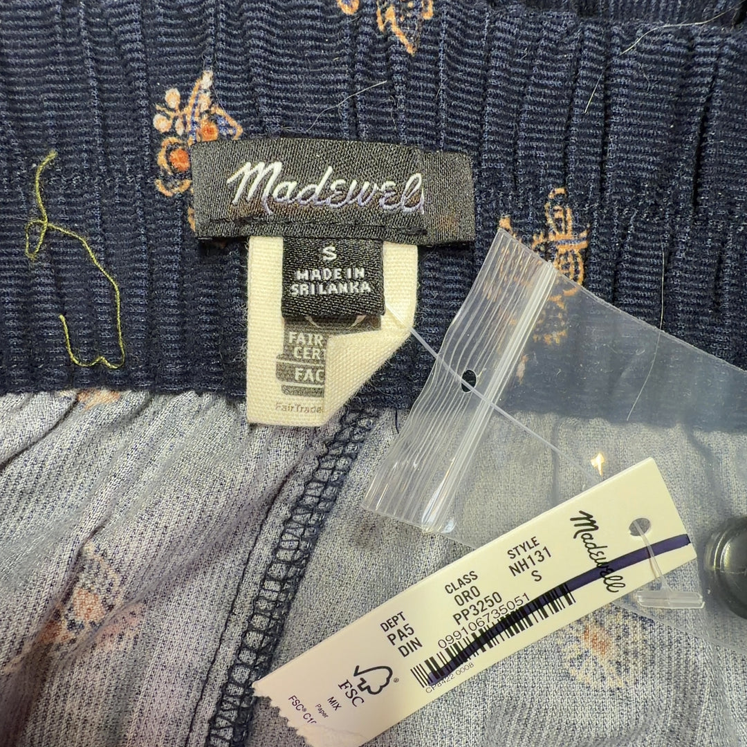Tag view of navy floral shorts showing relaxed fit and button-front closure detail