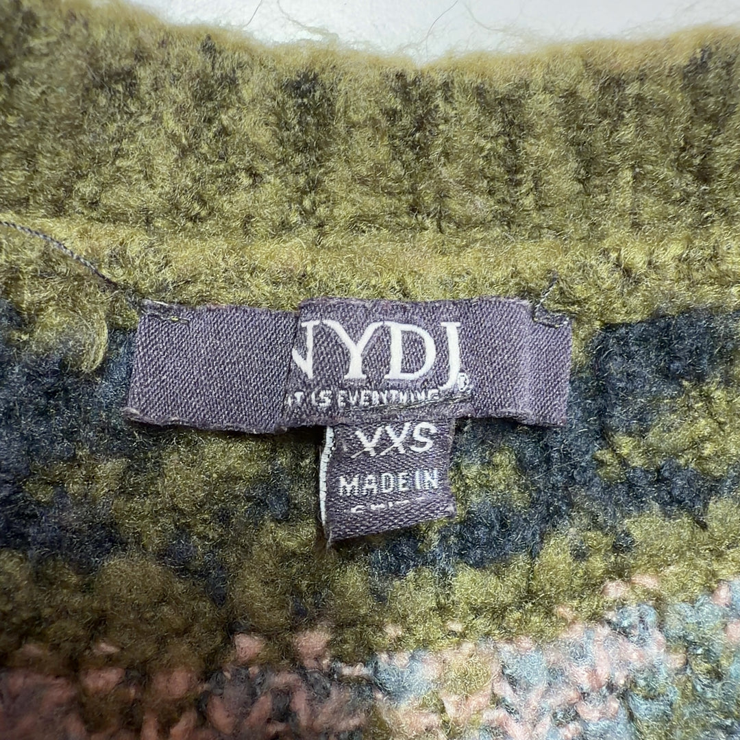 Tag view of olive Fair Isle cardigan showing patterned shoulders and cropped length, styled with black pants and gold heels
