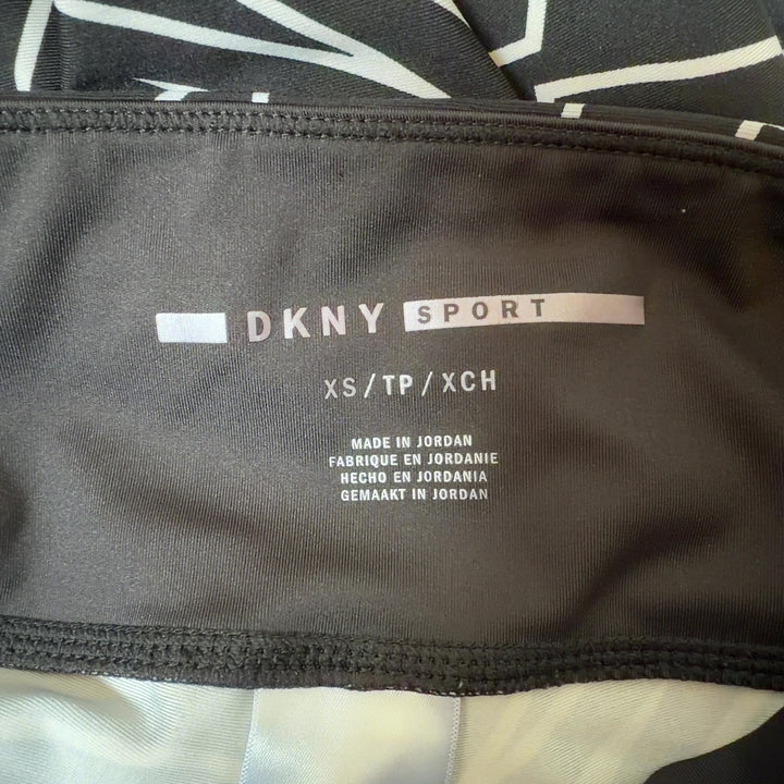 Black and white geometric print DKNY Sport leggings back view, showing side stripe detail and form-fitting silhouette