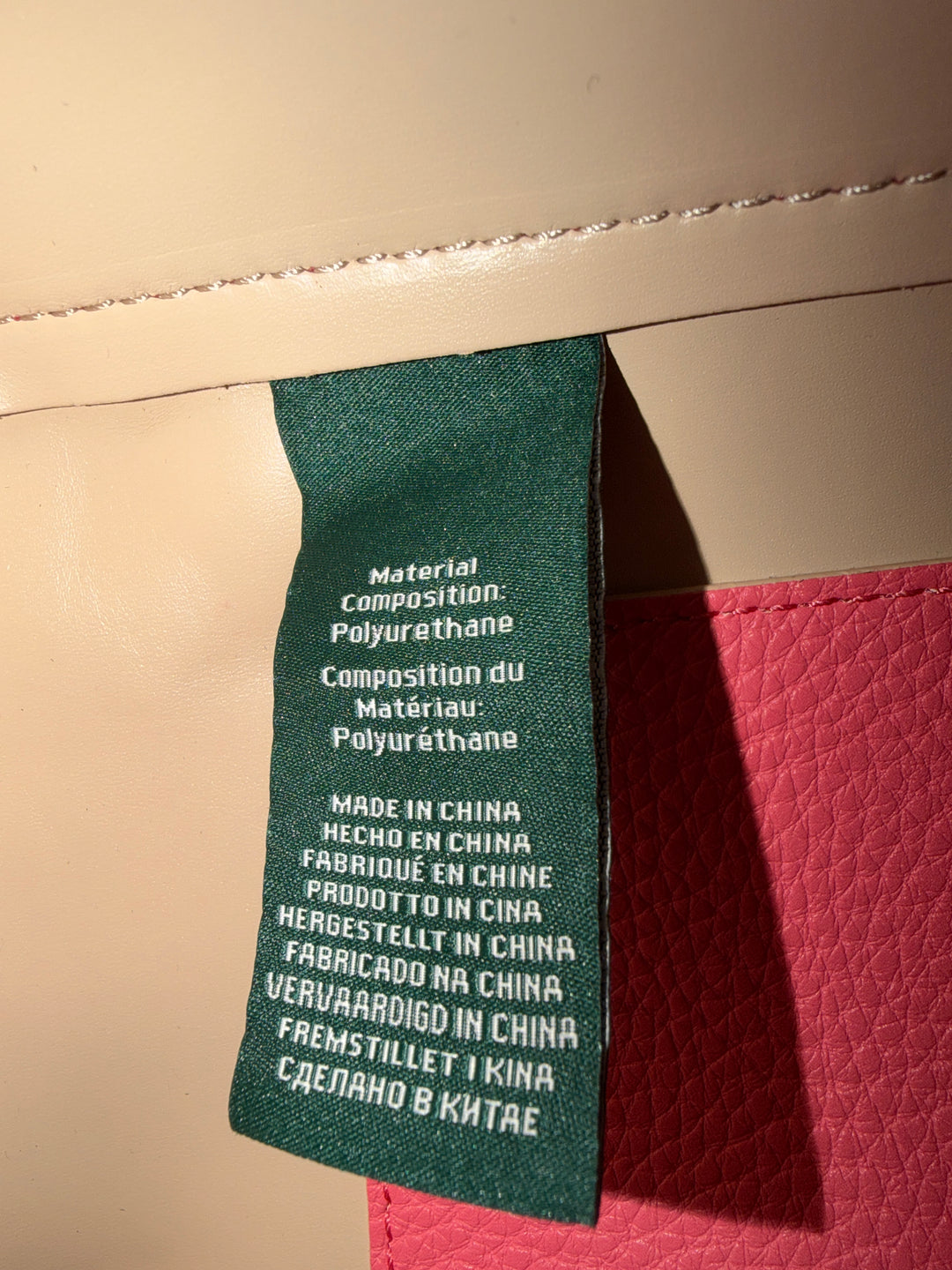 Tag view of pink Lauren Ralph Lauren tote bag worn on shoulder, showing structured silhouette and design details