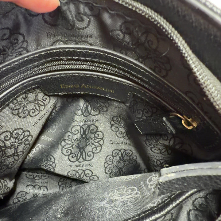 Tag view of black leather crossbody bag worn as crossbody style on model wearing black top
