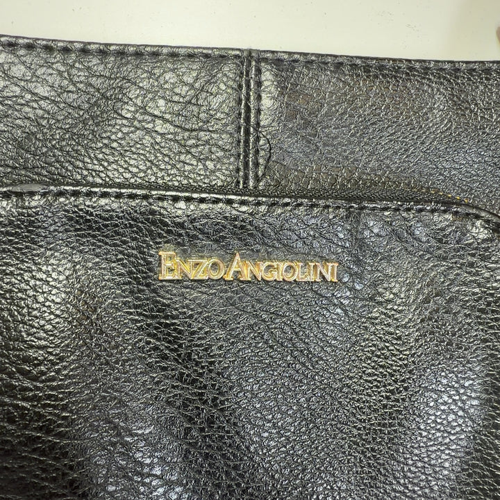 Tag view of black leather crossbody bag worn as crossbody style on model wearing black top