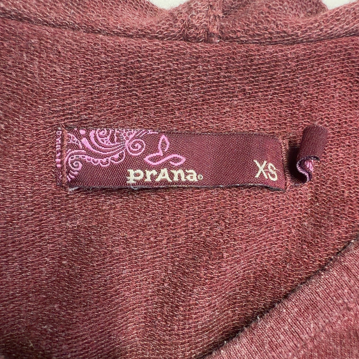Tag view of burgundy hooded dress showing damask print design and relaxed fit silhouette