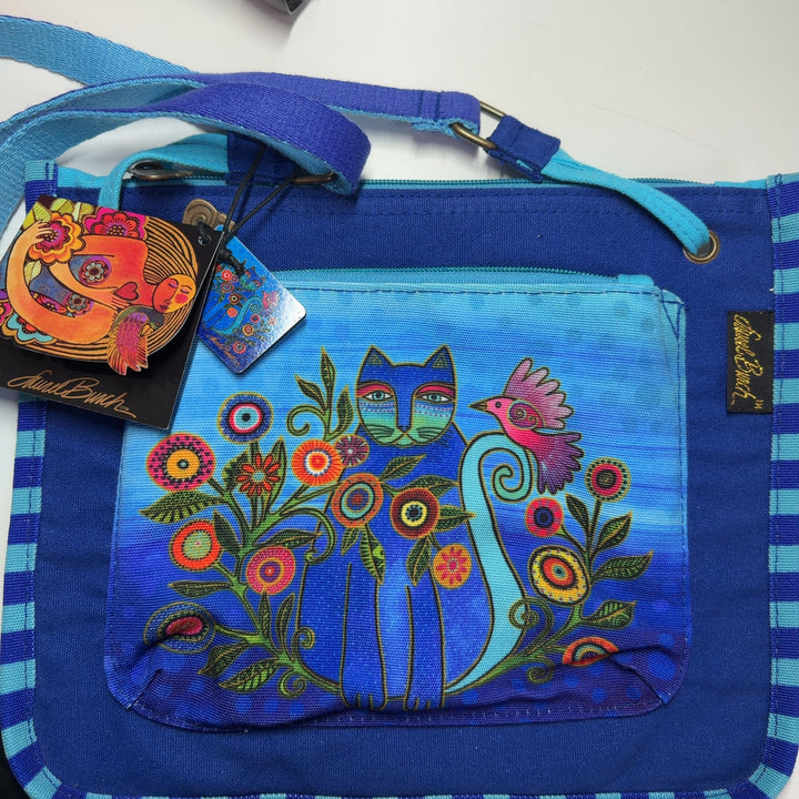 Tag view of blue canvas crossbody bag worn on shoulder showing adjustable light blue straps