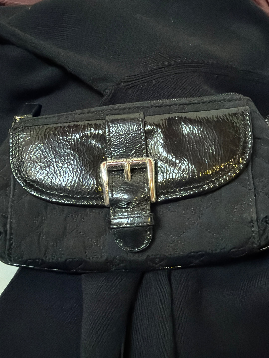 Woman wearing black leather crossbody bag by Brighton across body, demonstrating adjustable strap fit and compact size