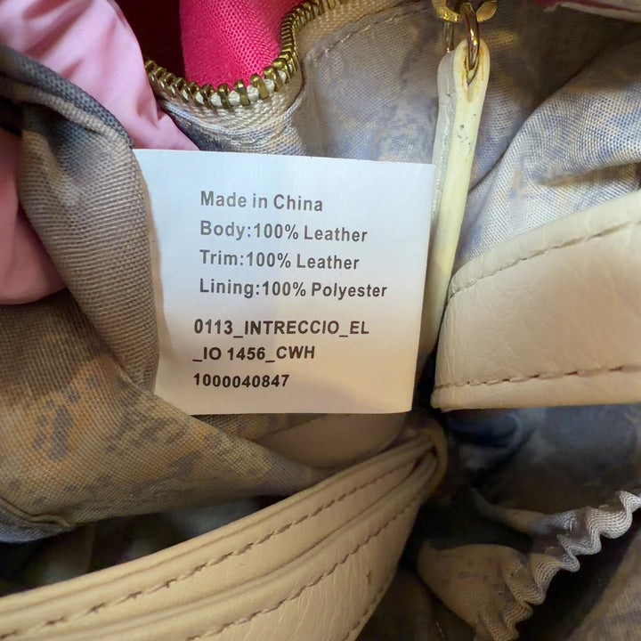 Tag view of cream leather crossbody bag worn on shoulder, showing quilted panel and overall silhouette