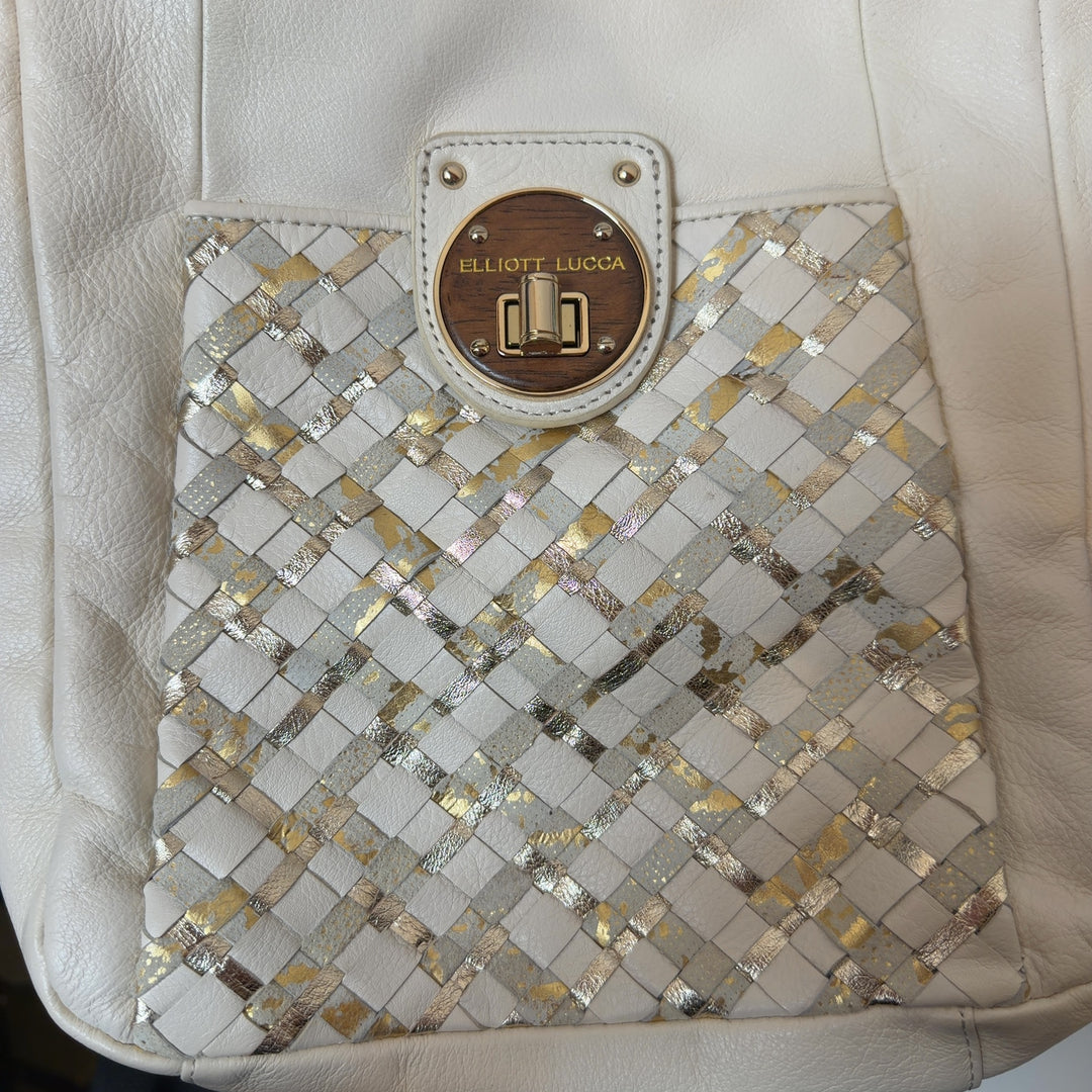 Tag view of cream leather crossbody bag worn on shoulder, showing quilted panel and overall silhouette