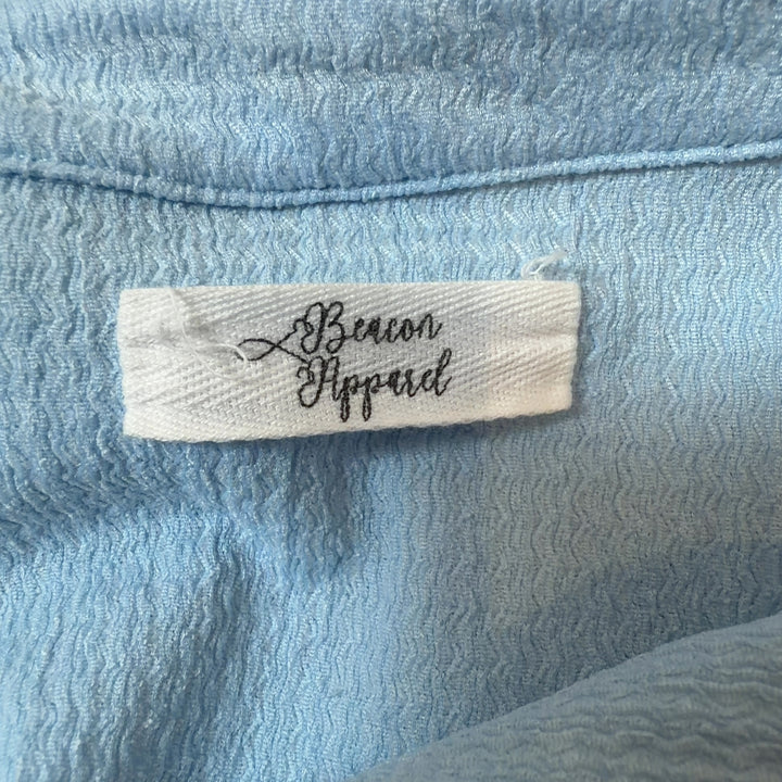 Tag view of light blue collared pullover top showing relaxed fit and gathered sleeve cuffs