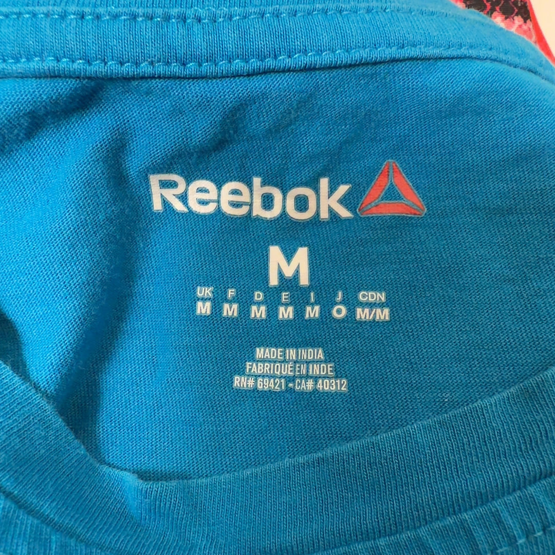 Blue Reebok graphic t-shirt back view showing distressed graphic design, worn with black leggings