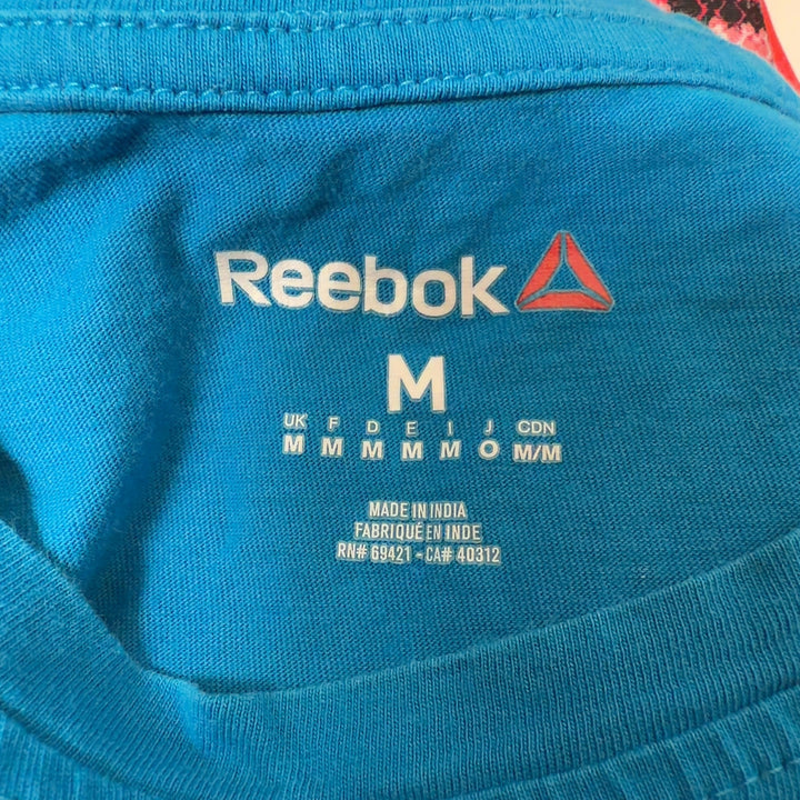 Blue Reebok graphic t-shirt back view showing distressed graphic design, worn with black leggings
