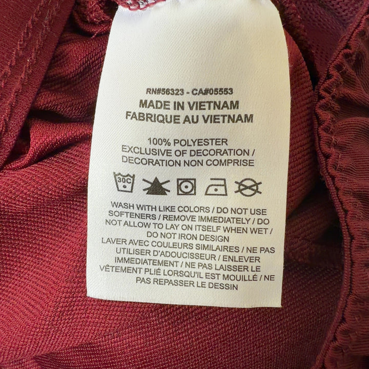 Tag view of burgundy Nike athletic shorts showing relaxed fit and length, styled with black sports bra