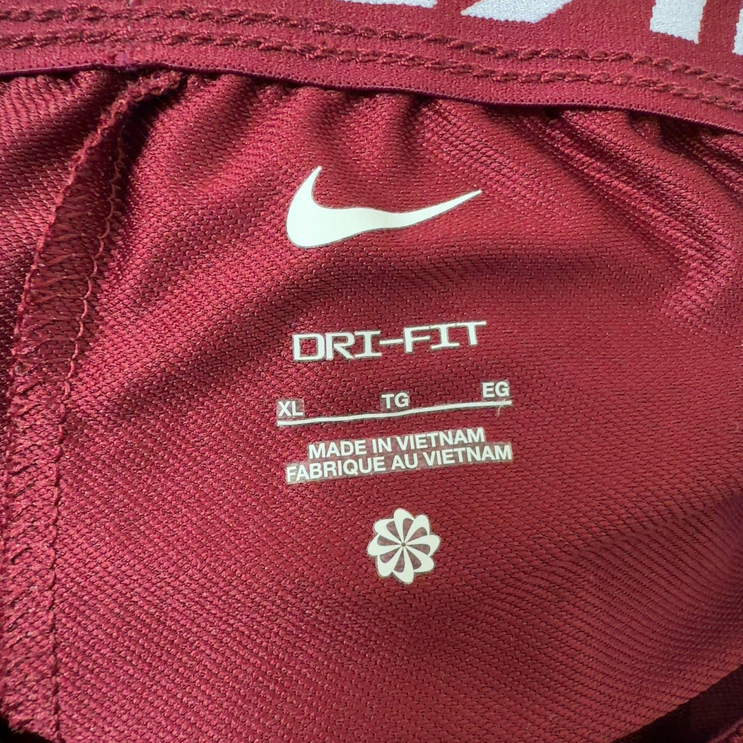 Tag view of burgundy Nike athletic shorts showing relaxed fit and length, styled with black sports bra