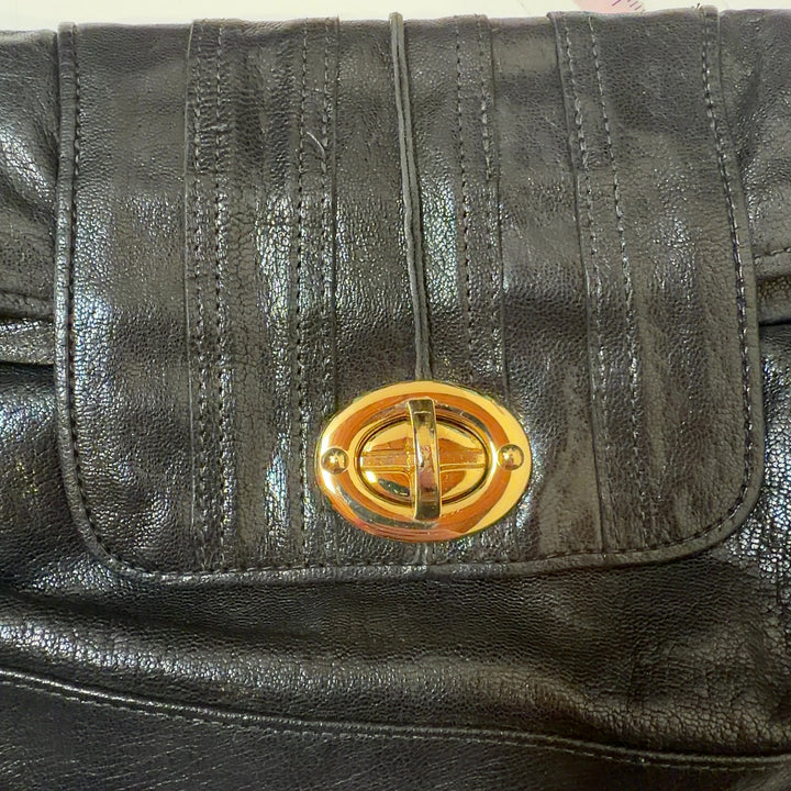 Black quilted leather clutch worn as a waist bag with gold hardware detail