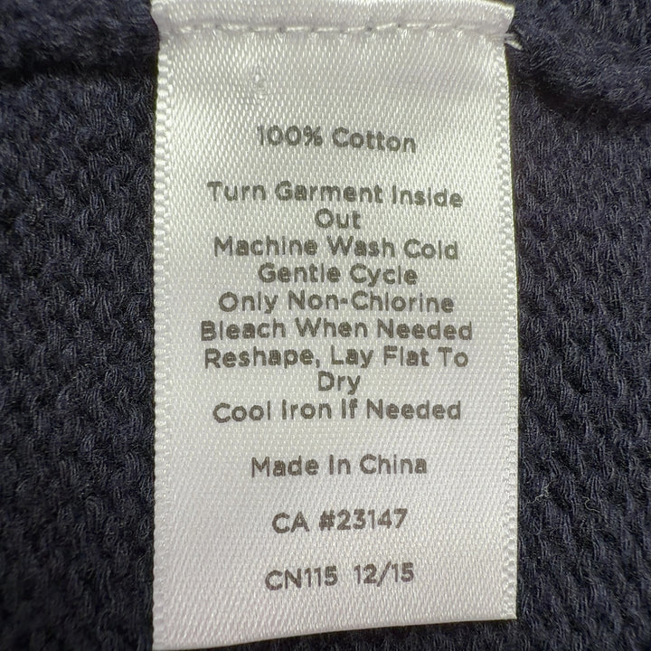 Black cotton cardigan with striped trim, back view showing zip closure and overall silhouette