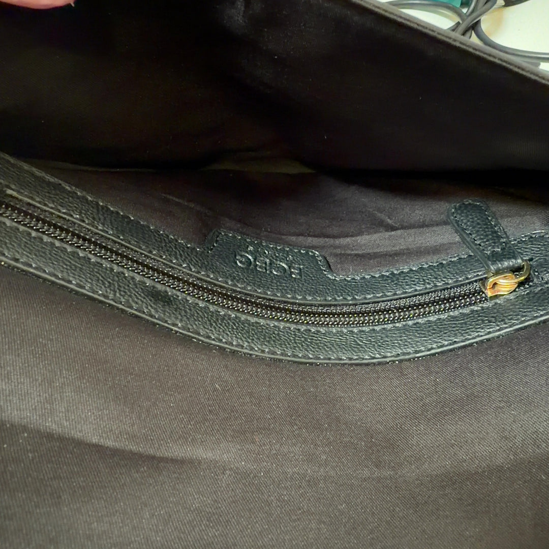 Black leather fold-over clutch styled with black outfit, showing back view and compact design